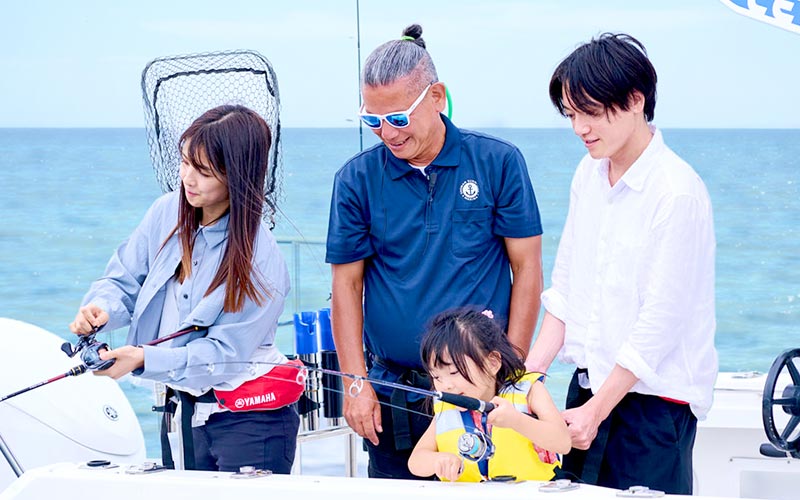 釣りを楽しむ父親、母親、娘と男性インストラクター